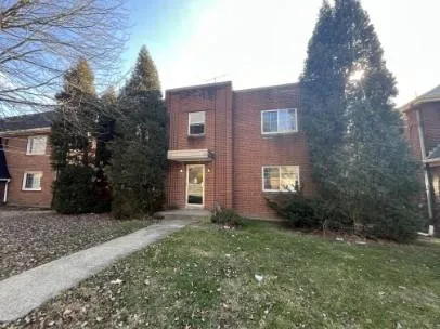 a brick house with a yard plants and large trees