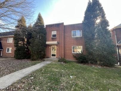 a brick house with a yard plants and large trees