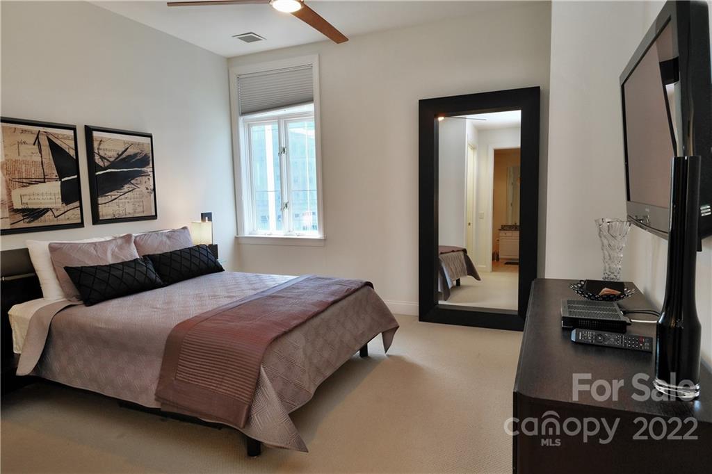 230 South Tryon Street, Unit 1109 Charlotte, NC 28202 - Photo 7 of 17 a bedroom with a bed and a large mirror next to a window