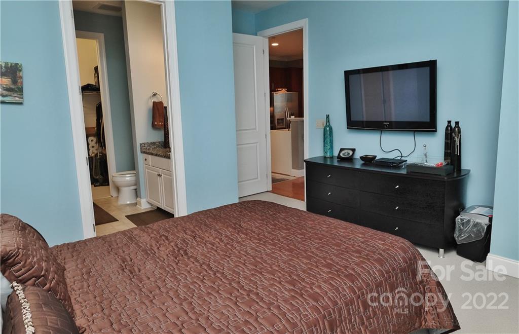 230 South Tryon Street, Unit 1109 Charlotte, NC 28202 - Photo 10 of 17 a bedroom with a bed and a flat tv screen on dresser