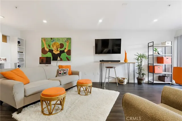 a living room with furniture kitchen view and a wooden floor