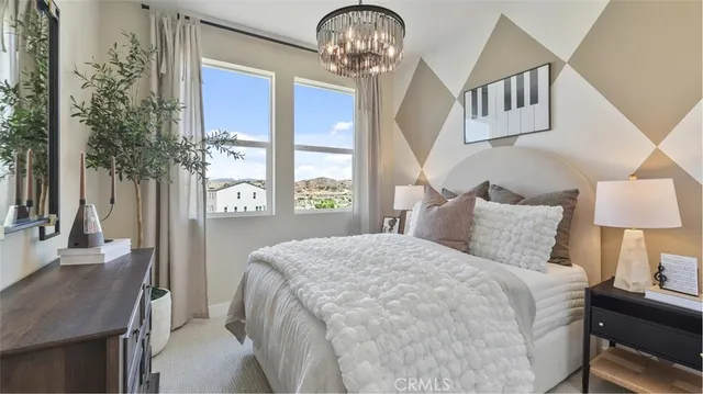 a bedroom with a bed a chandelier and dresser