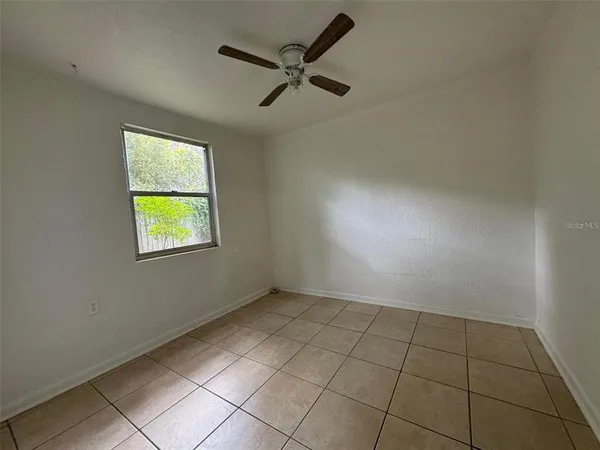 an empty room with windows and fan