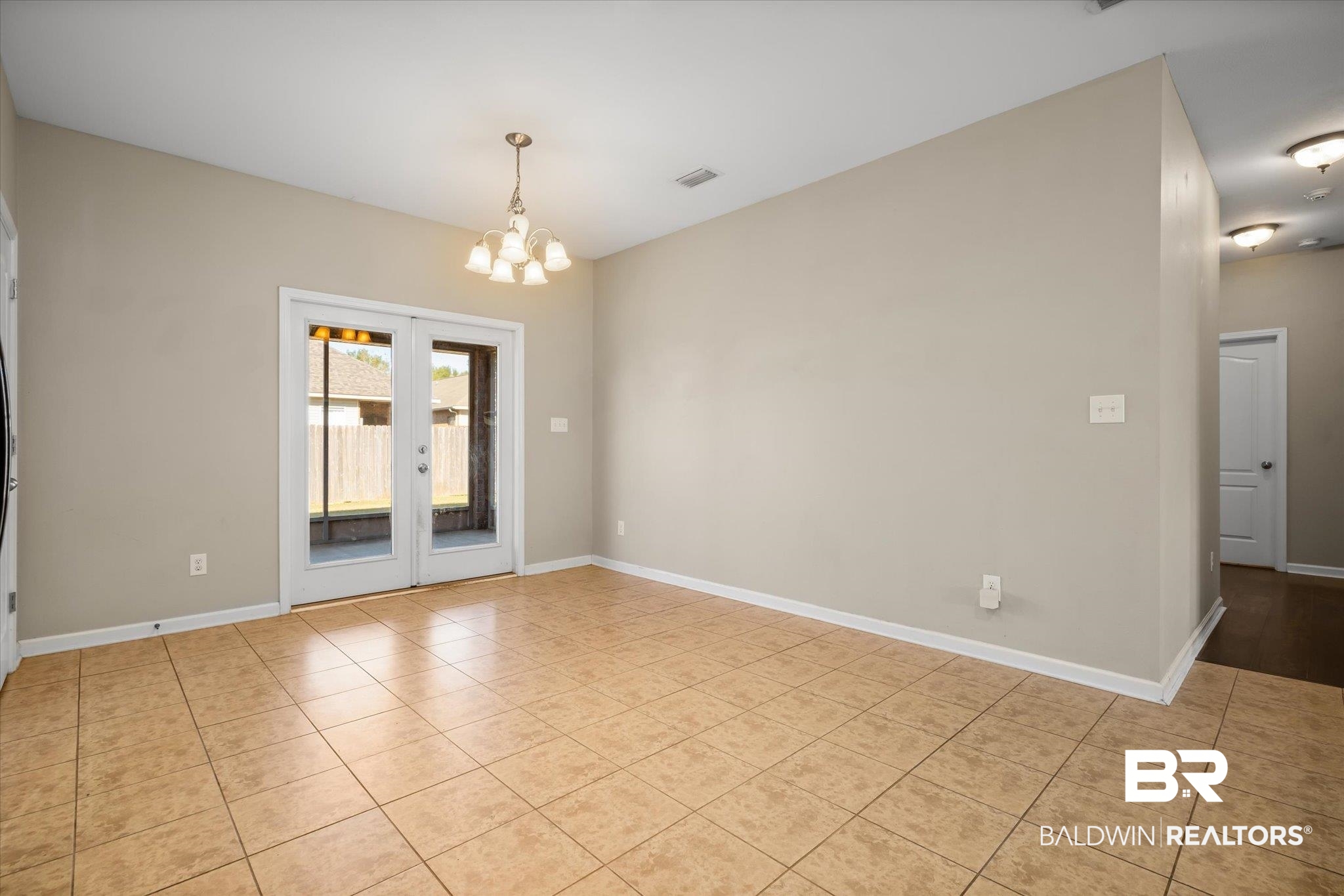 10251 Fionn Loop Daphne, AL 36526 - Photo 7 of 28 Spare room with light tile patterned floors and a notable chandelier
