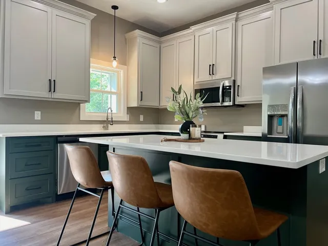 a kitchen with stainless steel appliances granite countertop a chairs a sink and a refrigerator