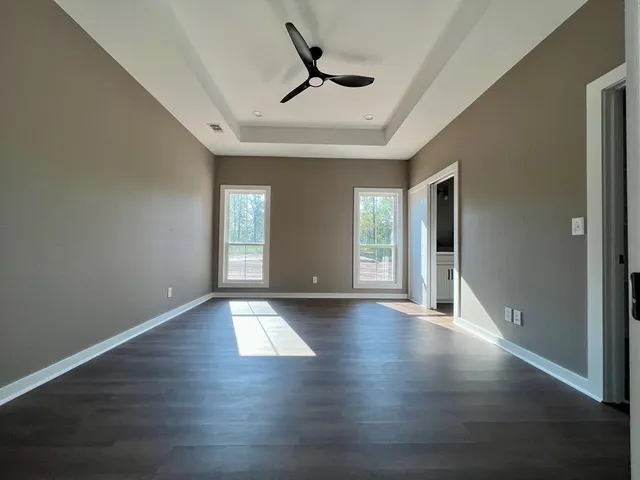 a view of an empty room with window and wooden floor