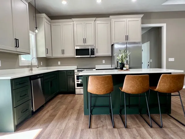 a kitchen with stainless steel appliances granite countertop a table chairs sink and cabinets