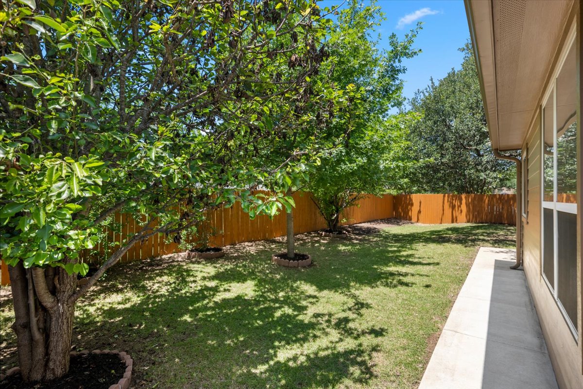 3451 Mayfield Ranch Boulevard, Unit 311 Round Rock, TX 78681 - Photo 40 of 40 Spacious backyard featuring a manicured lawn, established shade trees, and a wooden privacy fence