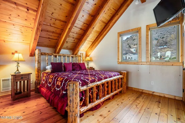 a bedroom with a bed next to a window with wooden floor