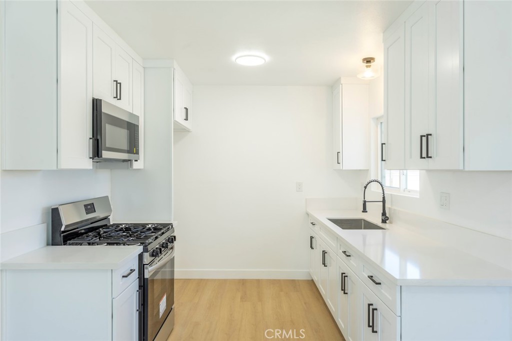 1218 6th Street Redlands, CA 92374 - Photo 5 of 16 a kitchen with stainless steel appliances a sink stove top oven and white cabinets