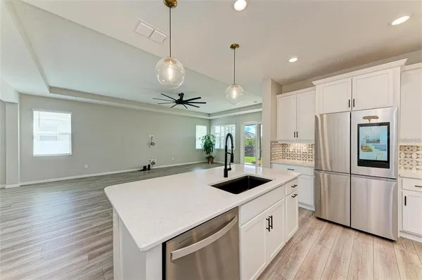 a kitchen with a refrigerator a sink and wooden floor