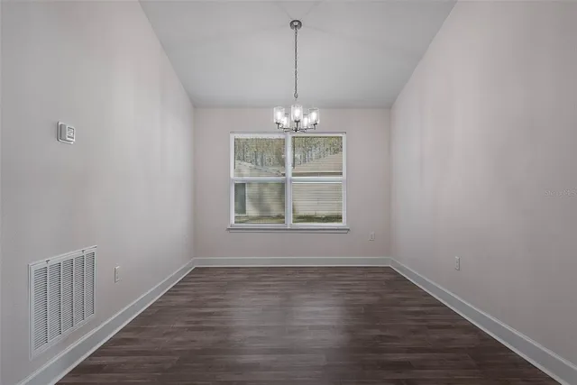 an empty room with wooden floor cabinet and windows