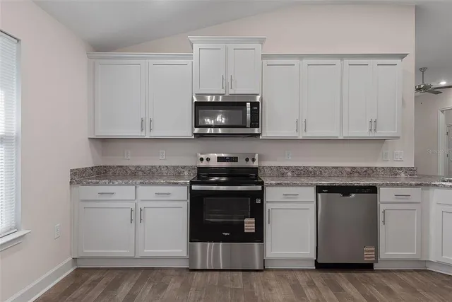 a kitchen with granite countertop white cabinets and stainless steel appliances