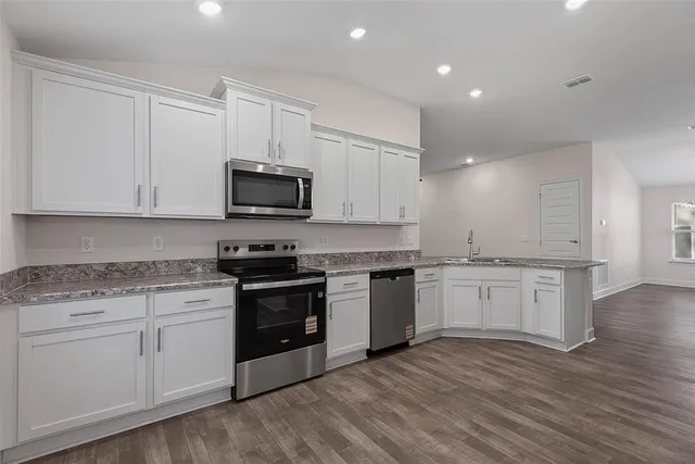 a kitchen with granite countertop stainless steel appliances white cabinets and a granite counter tops