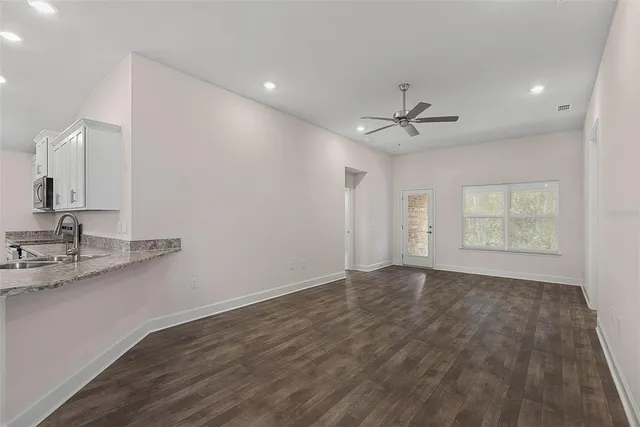 a view of an empty room with a window and a kitchen view