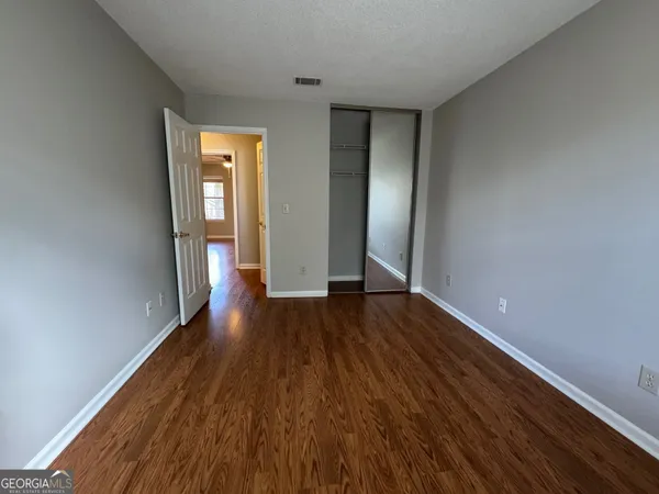 a view of an empty room with wooden floor and closet