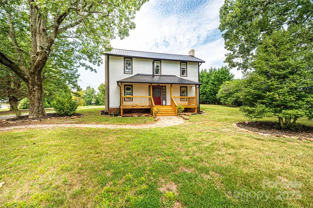 a view of house with yard outdoor seating and covered with trees