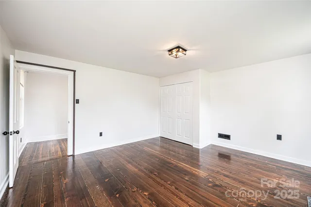 an empty room with windows fireplace and wooden floor