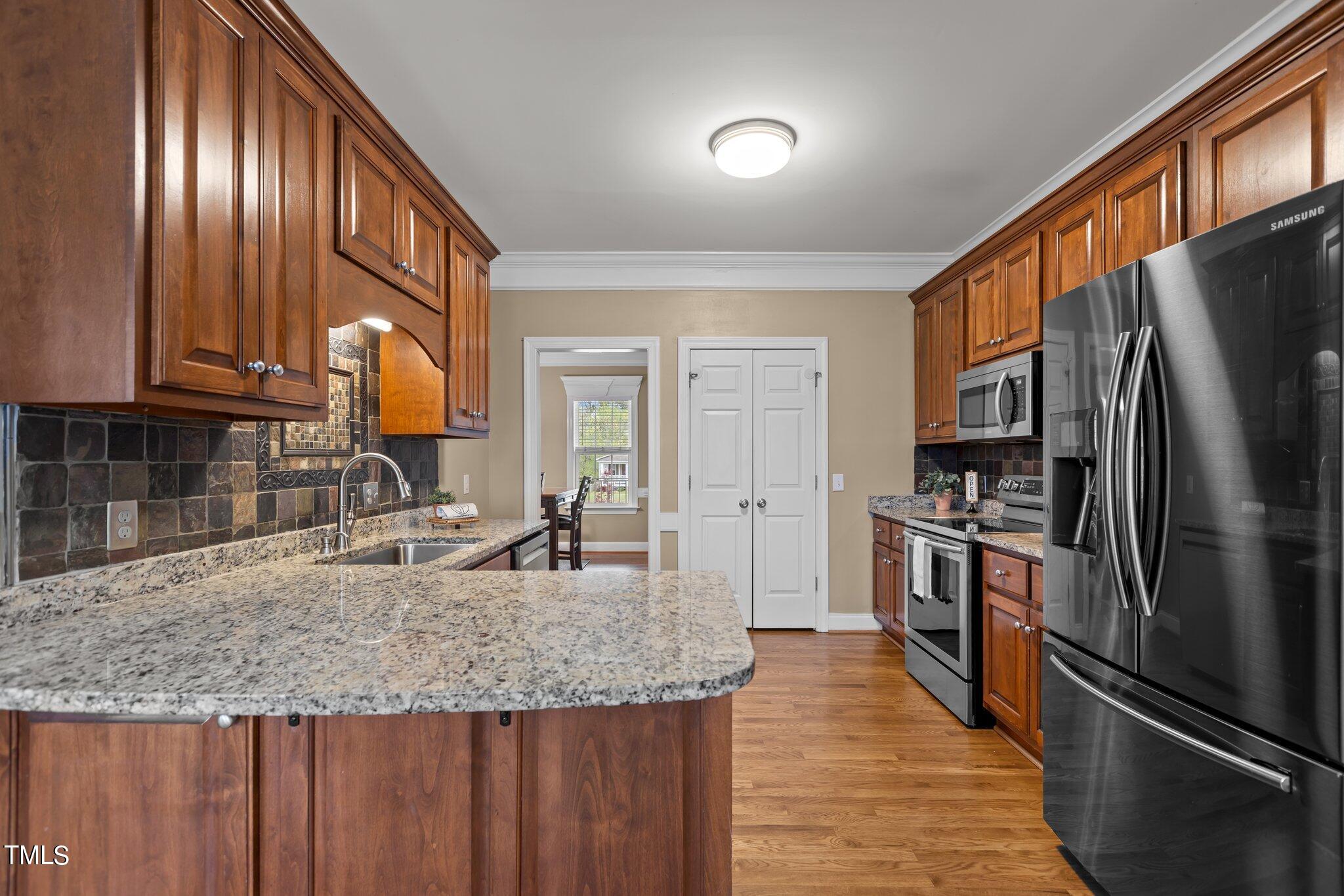 148 Ina Joe Place Willow Spring, NC 27592 - Photo 8 of 41 a kitchen with stainless steel appliances granite countertop a refrigerator a stove and a sink with wooden floors