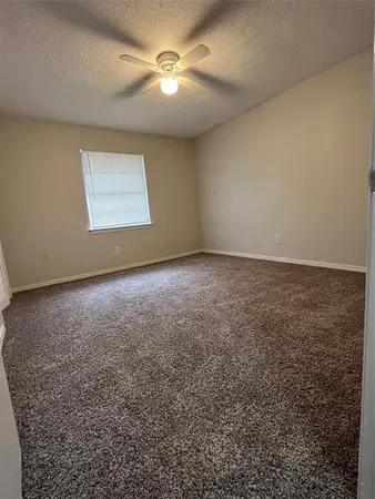 an empty room with a fan & a window