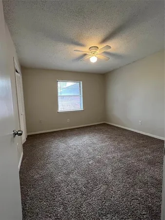 an empty room with a ceiling fan and window