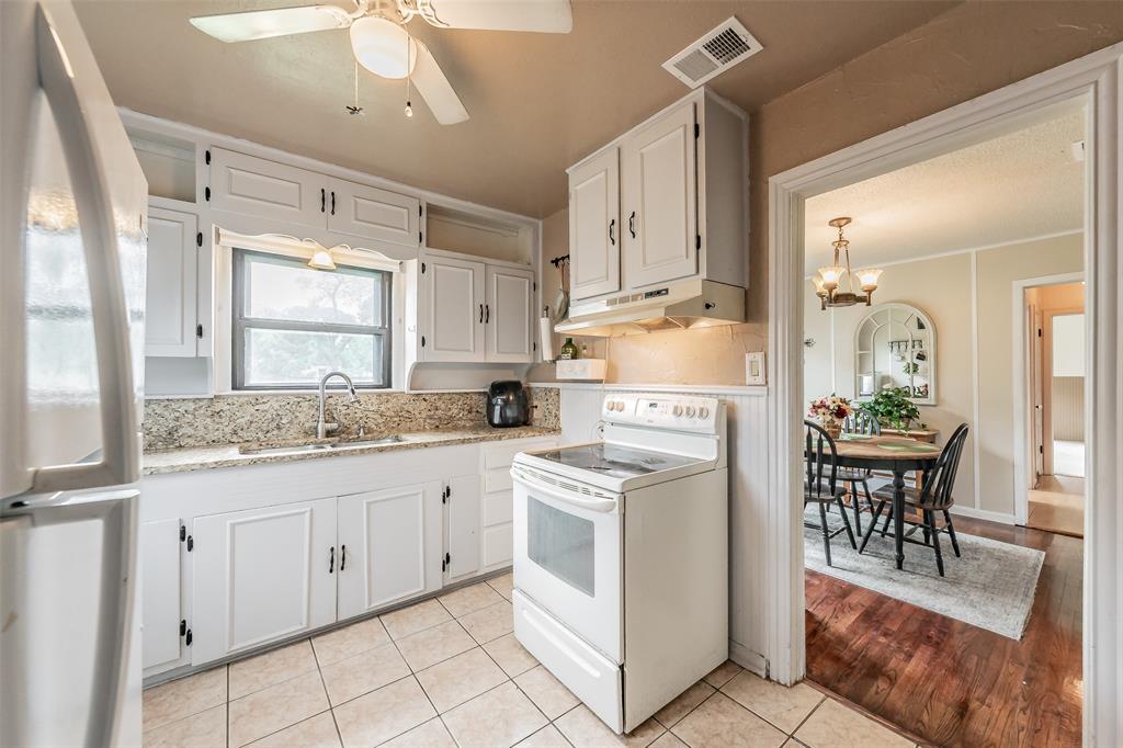 1802 Keneipp Road Carrollton, TX 75006 - Photo 14 of 22 The kitchen features white cabinetry, granite countertops, and tiled flooring