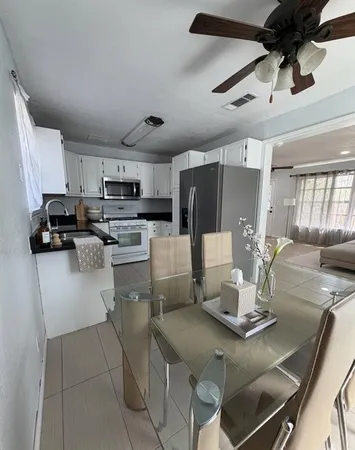 a kitchen with a table chairs refrigerator and microwave