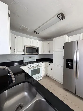 a kitchen with stainless steel appliances a refrigerator sink and white cabinets
