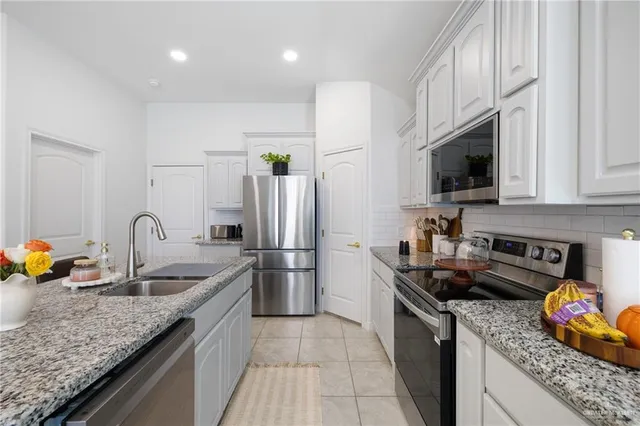 a kitchen with granite countertop a sink a counter top space appliances and cabinets