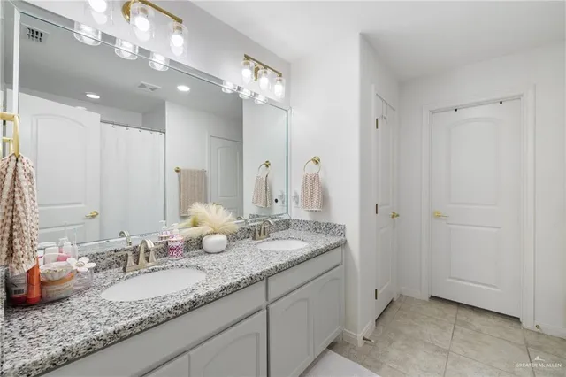 a bathroom with a granite countertop double vanity sink and a mirror