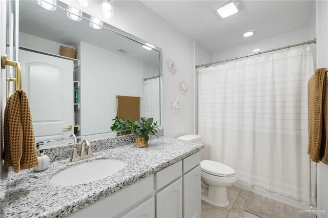 a bathroom with a granite countertop sink and a mirror a toilet