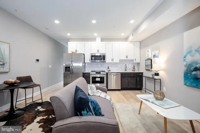 a kitchen with stainless steel appliances granite countertop a stove top oven a sink dishwasher a dining table and chairs with wooden floor