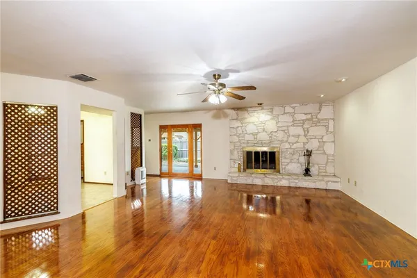 a view of an empty room with a fireplace and wooden floor