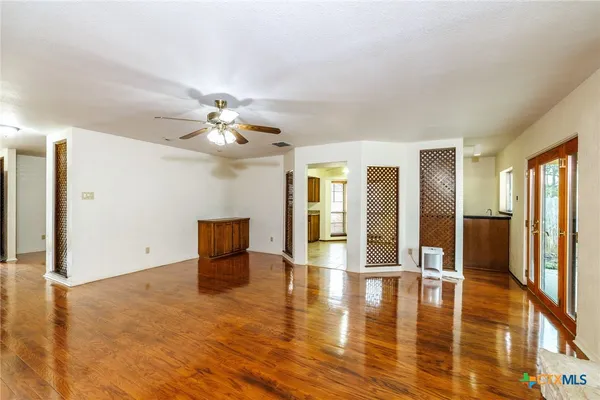 a view of an empty room with window and wooden floor