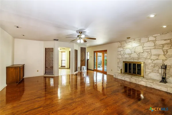 a view of an empty room with a fireplace and wooden floor