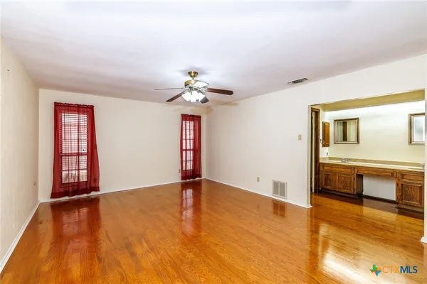 a view of an empty room with window and wooden floor