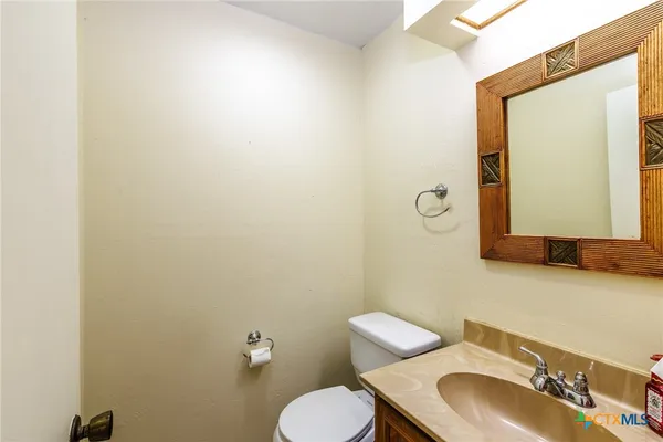 a bathroom with a toilet sink mirror and vanity
