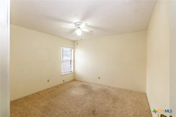 an empty room with windows and fan