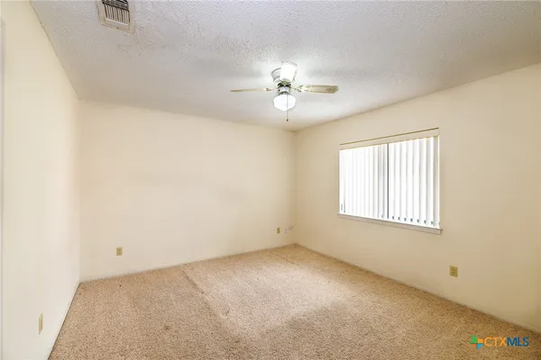 an empty room with a window and a ceiling fan