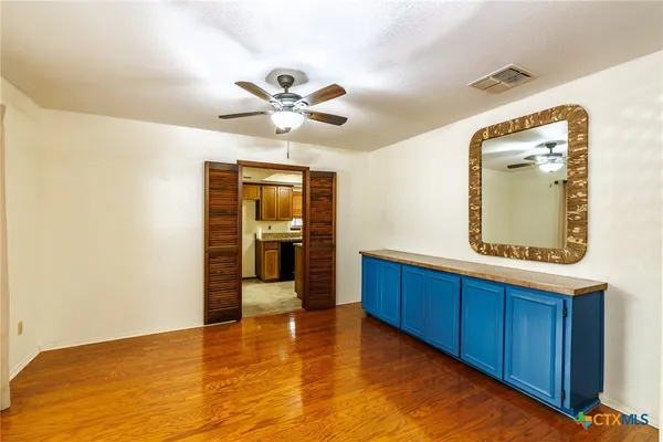 a view of a hallway with wooden floor and a bathroom