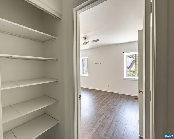 a view of an empty room with a window and wooden floor