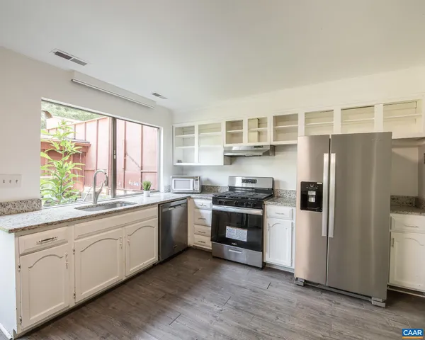 a kitchen with stainless steel appliances granite countertop a refrigerator a sink dishwasher a stove with wooden floors and cabinets