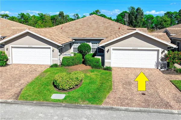a view of a white house with a small yard and a large tree front of it
