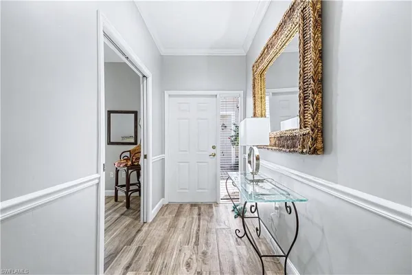 a view of a hallway with wooden floor and a bathroom