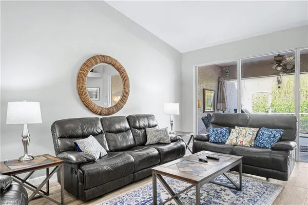 a living room with furniture a mirror a lamp and a large window