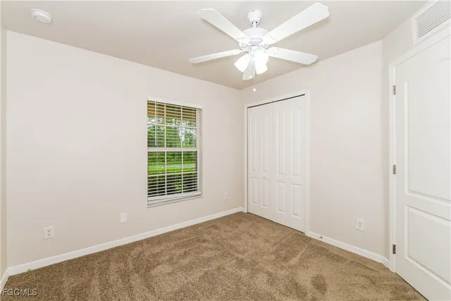 an empty room with windows and fan