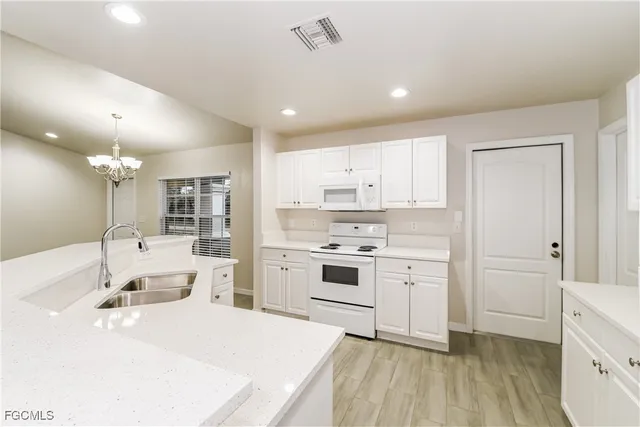 a room with a white bed cabinets and a window