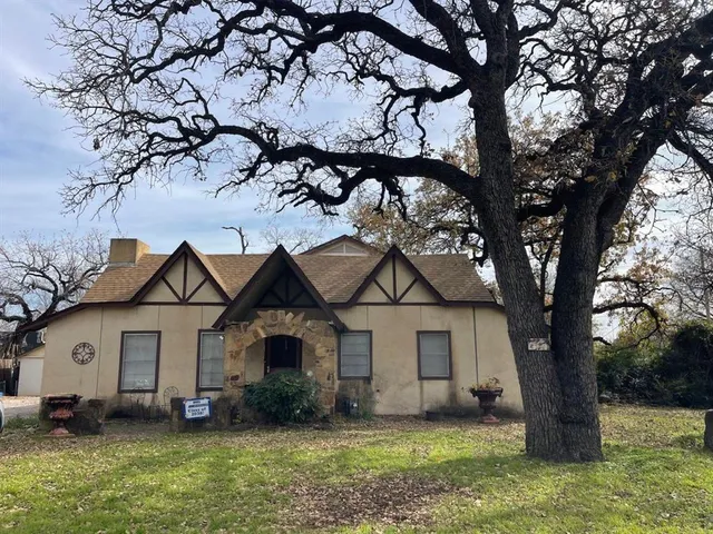 a view of a yard in front of a house with large tree