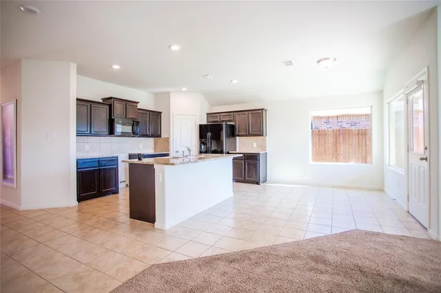 a large white kitchen with kitchen island granite countertop a large counter top stainless steel appliances and cabinets