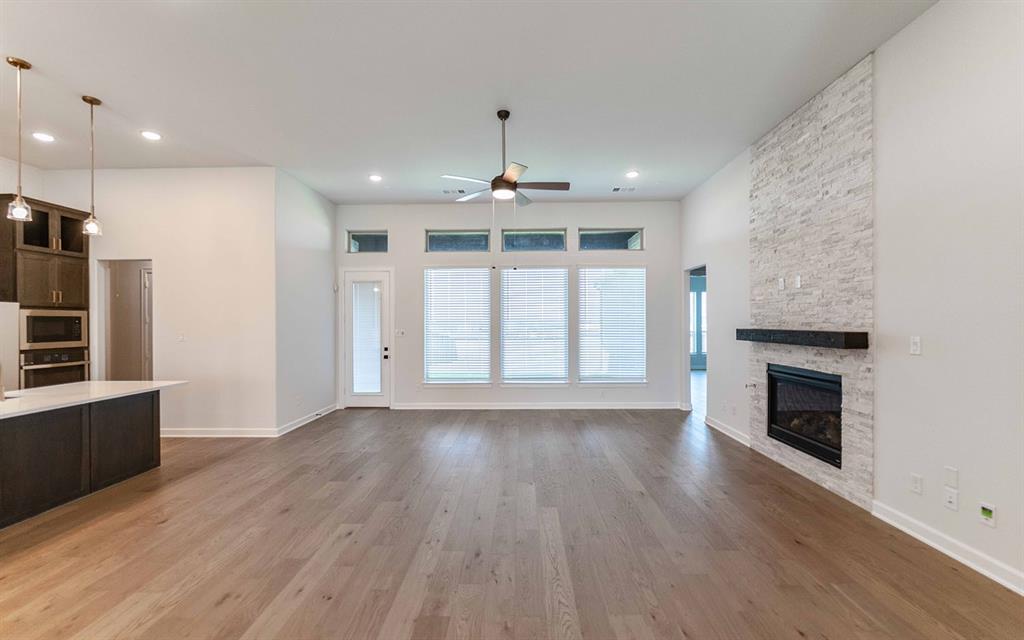 2008 Casting Ridge Mesquite, TX 75181 - Photo 13 of 24 Open-concept living area with wood-finish flooring, a contemporary fireplace featuring a light stacked stone surround and dark mantel, and multiple windows